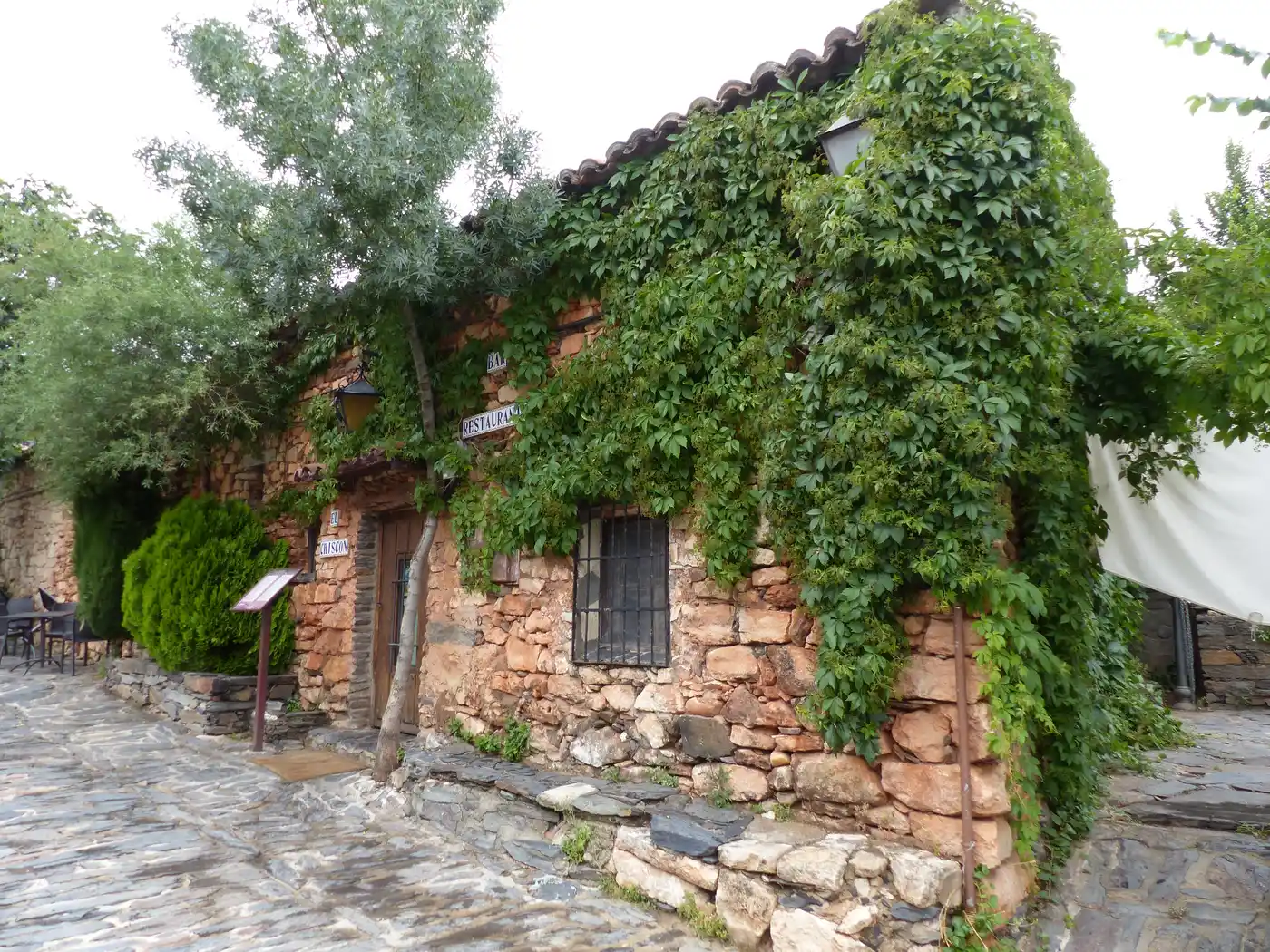 Calle empedrada de Patones de Arriba con casas de pizarra negra, sin gente